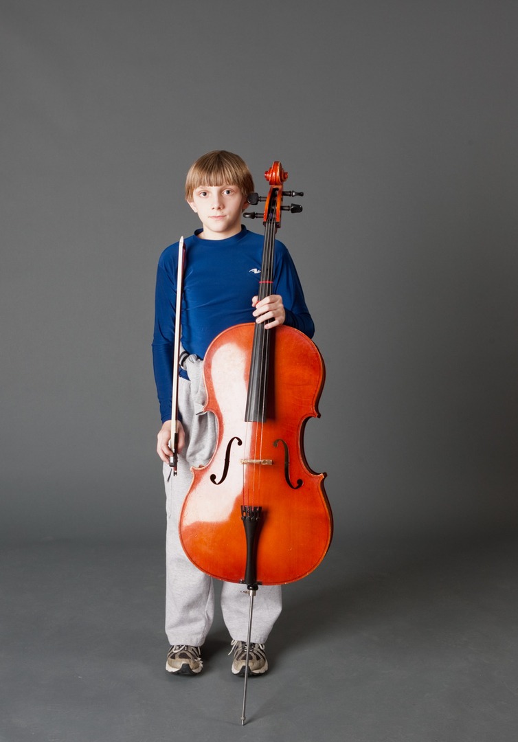 a boy in a blue shirt holding a cello