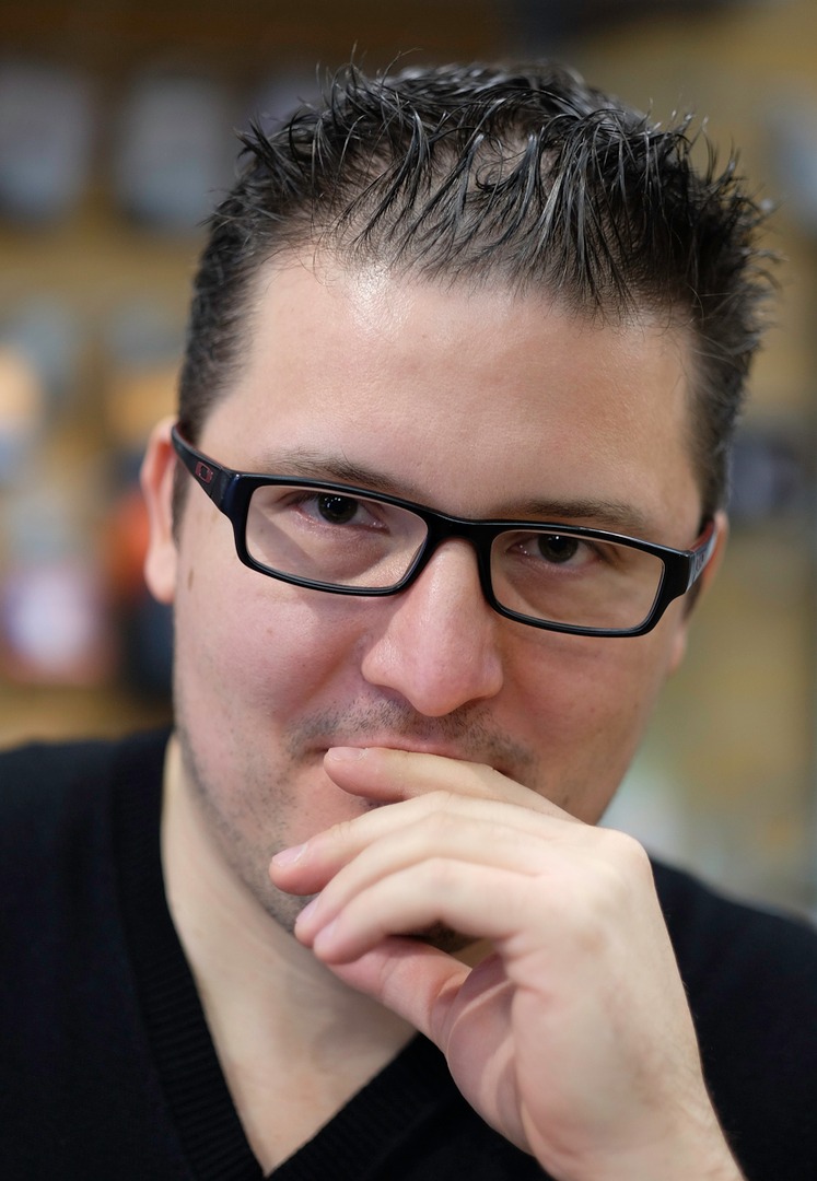 A man in a black shirt with black glasses