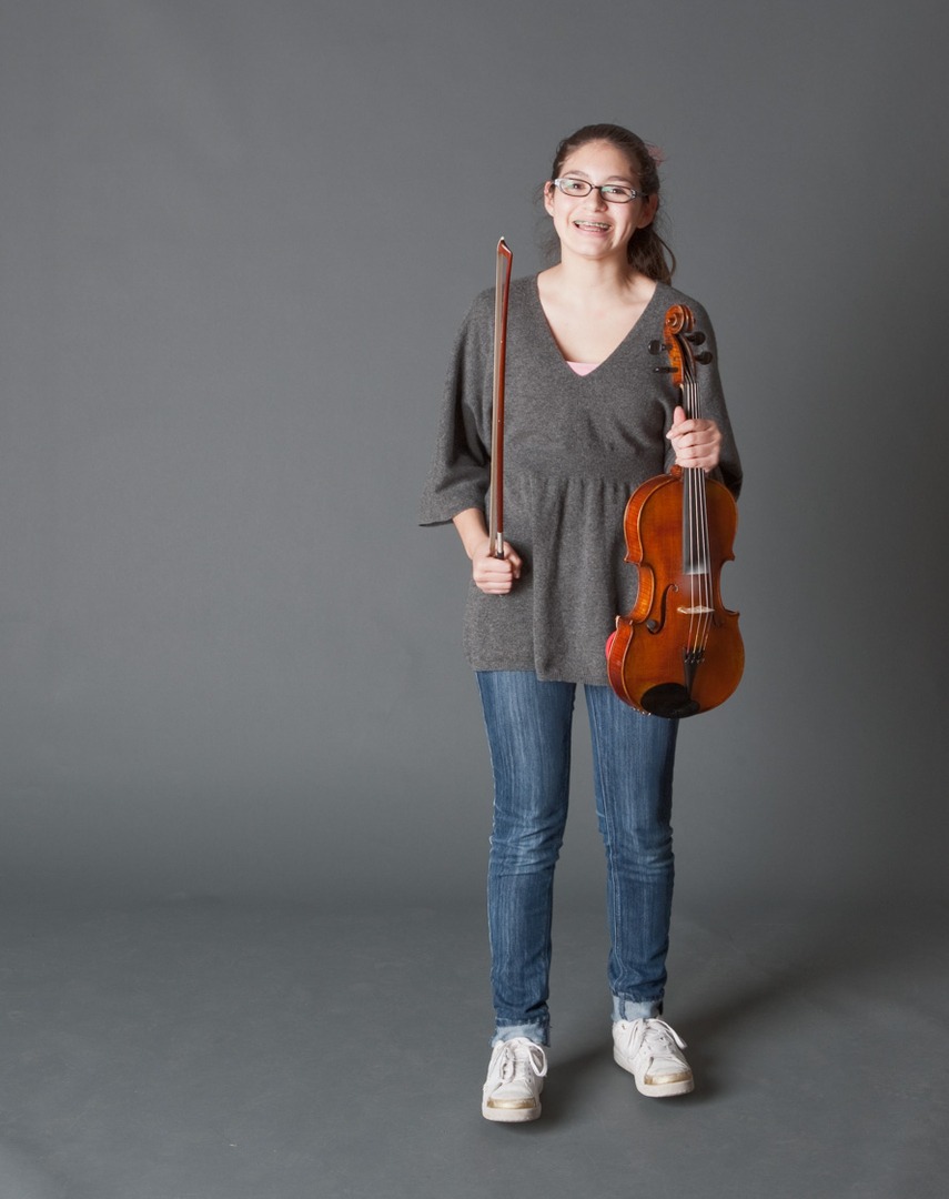 a girl in a gray shirt holding a violin