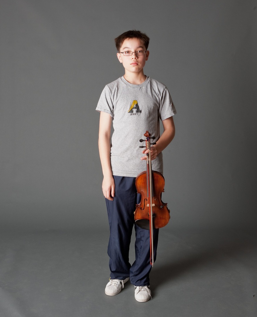 a boy in a gray shirt holding a violin