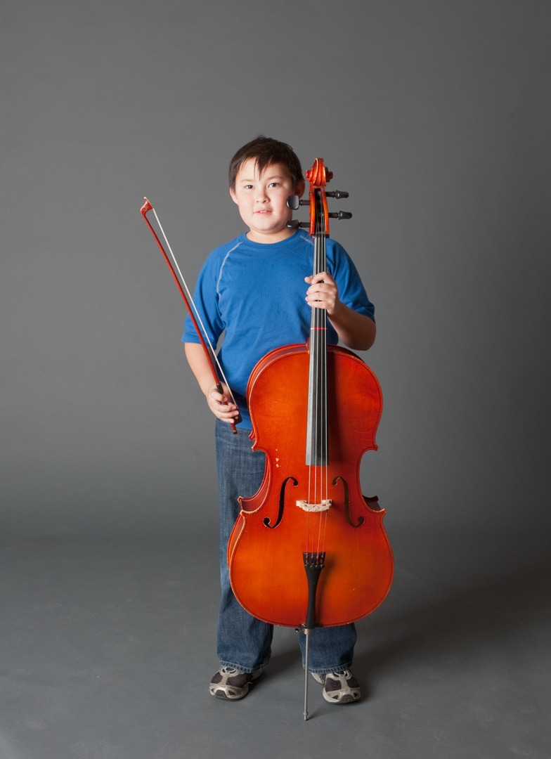 a boy in a blue shirt holding a cello